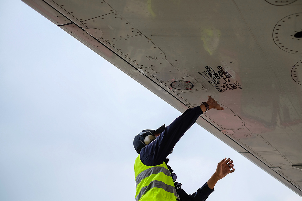 Image of aircraft technician in a yellow vest working under a wing