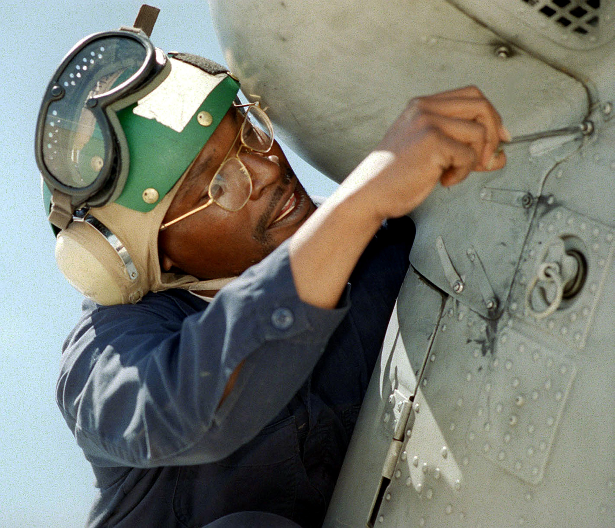 Image of an aviation structural mechanic fixing a fastener on a tail gear box panel.