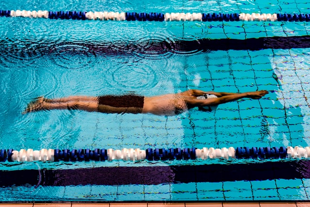Swimmer in pool with arms extended in in direction of movement