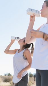 Image of two pepole drinking boxed water outdoors.