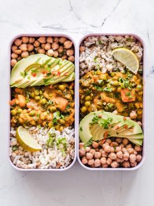Image of two pre-made lunches with chickpeas, avocado slices, rice and vegetables