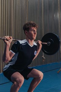 Image of a person doing a squat with a barbell across the shoulders.
